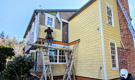 Crew working on installing new, yellow siding and windows on a home to illustrate best exterior house improvements.