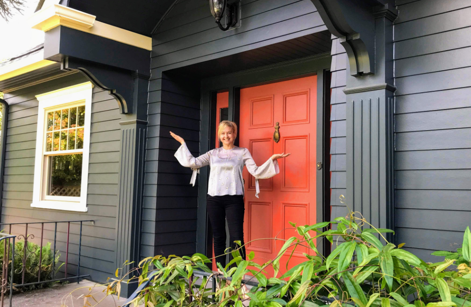 A happy woman in front of a newly sided home to illustrate what's HELOC